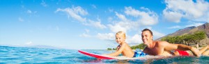 father paddling on surfboard with son