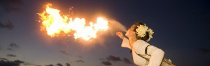 A woman breathes fire at a luau overlooking the Pacific Ocean