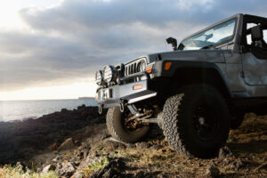 Low angle view of front of SUV on a rocky beach. Horizontal format.